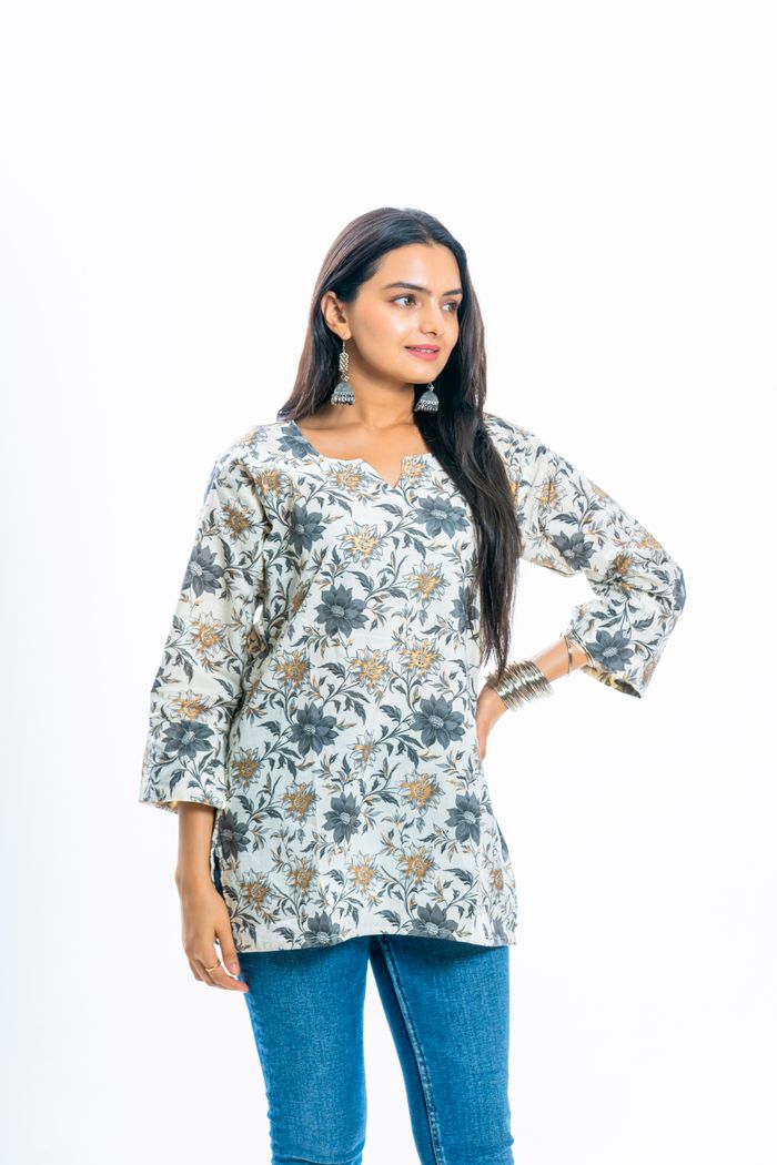 Woman in floral tunic with earrings and bangles posing gracefully.