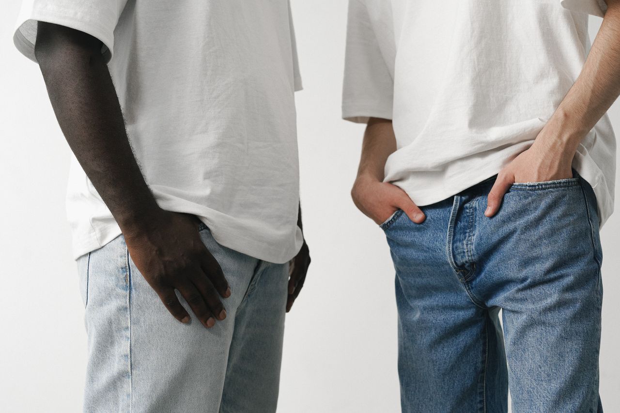 Close-up of two adults in white shirts and denim jeans, showcasing casual fashion style.
